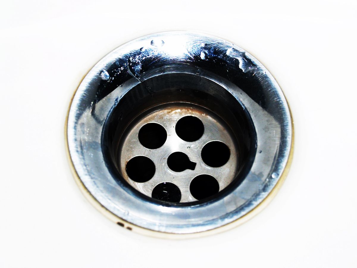 Close-up of a chrome sink drain with water