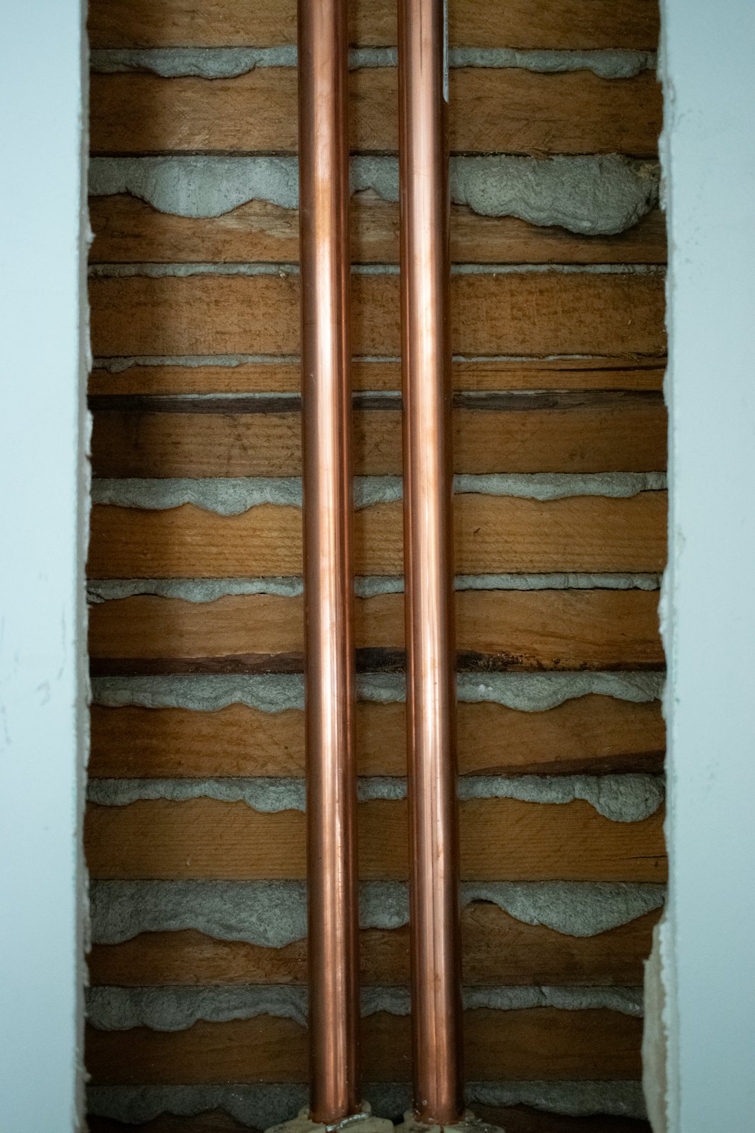 Two copper supply pipes installed along a wall