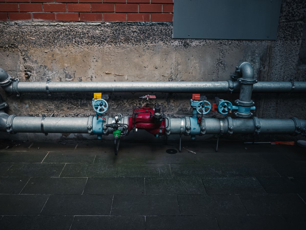 Pipes with color-coded valves along a wall