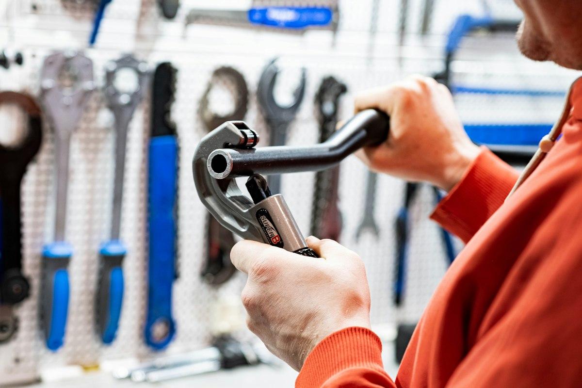 Technician holding a pipe wrench in front of a tool wall
