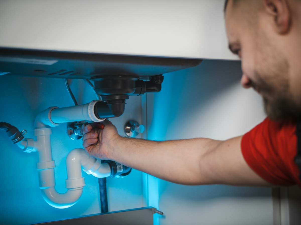 Plumber repairing the drain pipe under a sink