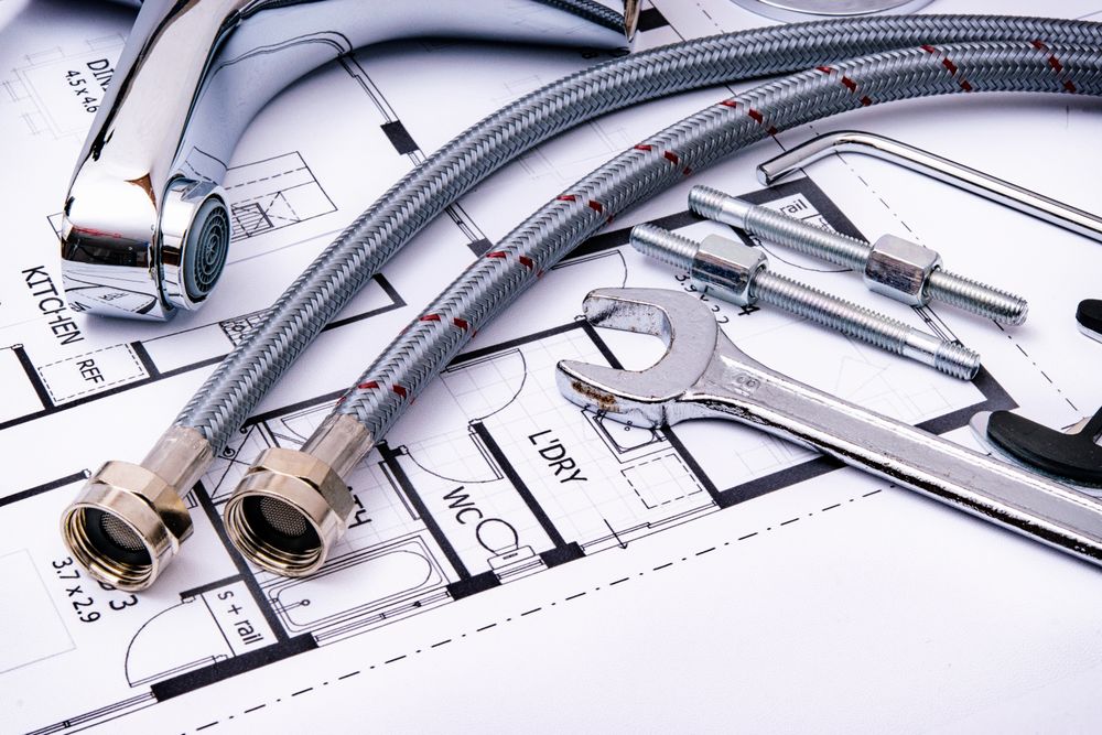 Plumbing tools and flexible hoses on top of a building blueprint