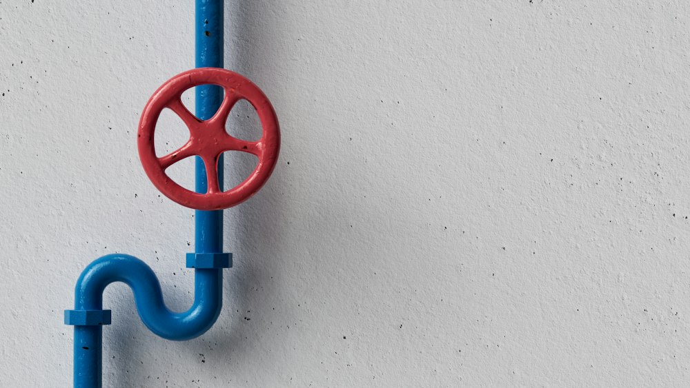 Red shut-off valve on a blue water pipe