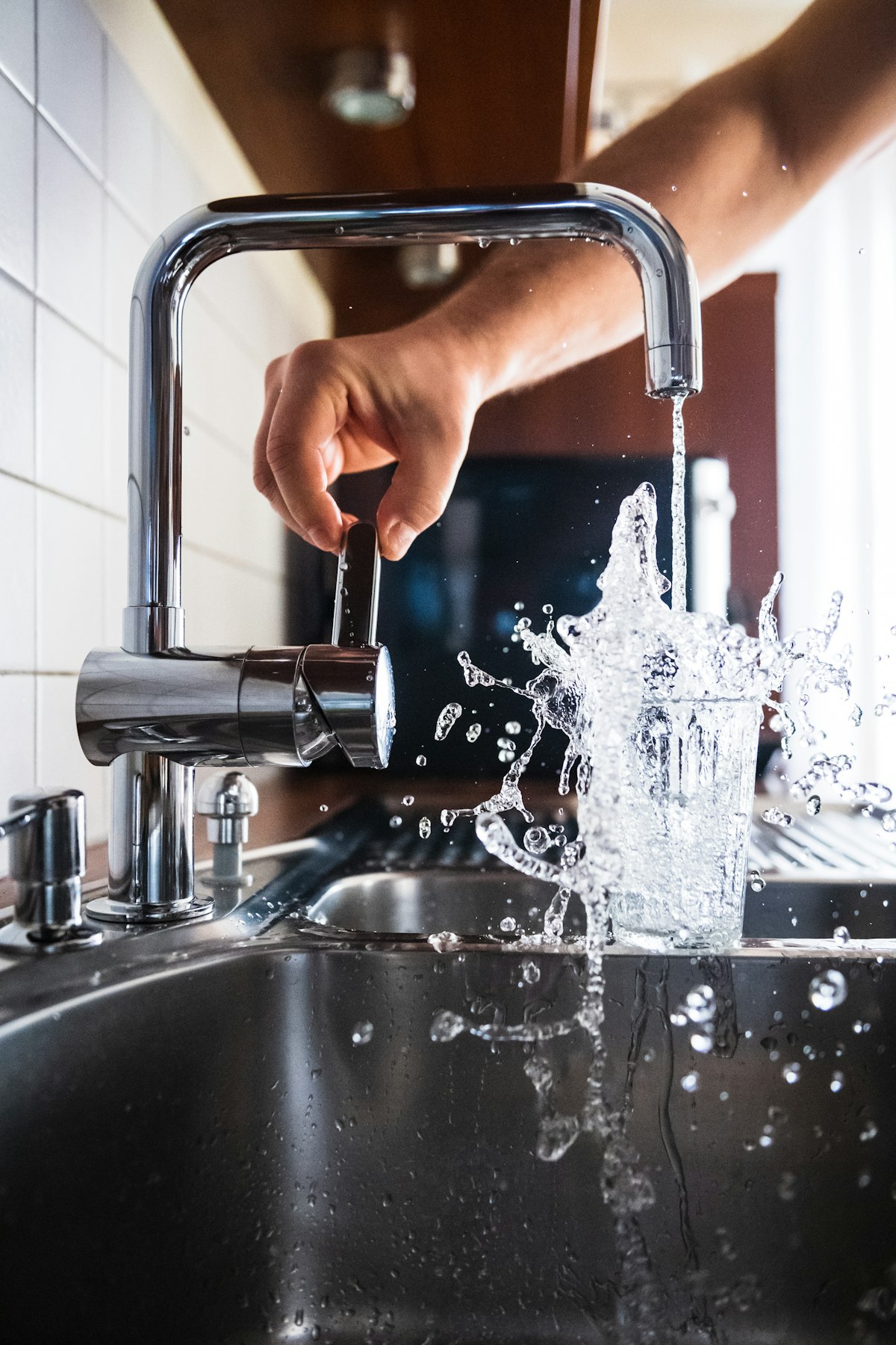 Repairing a leaking faucet with a wrench while water sprays